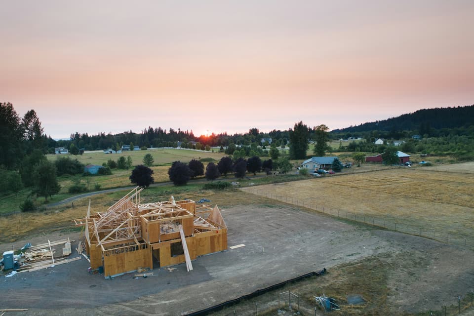 Timber framing for a new building on open land at sunset