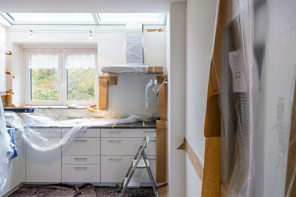 A kitchen mid-renovation with cabinets wrapped in plastic sheeting